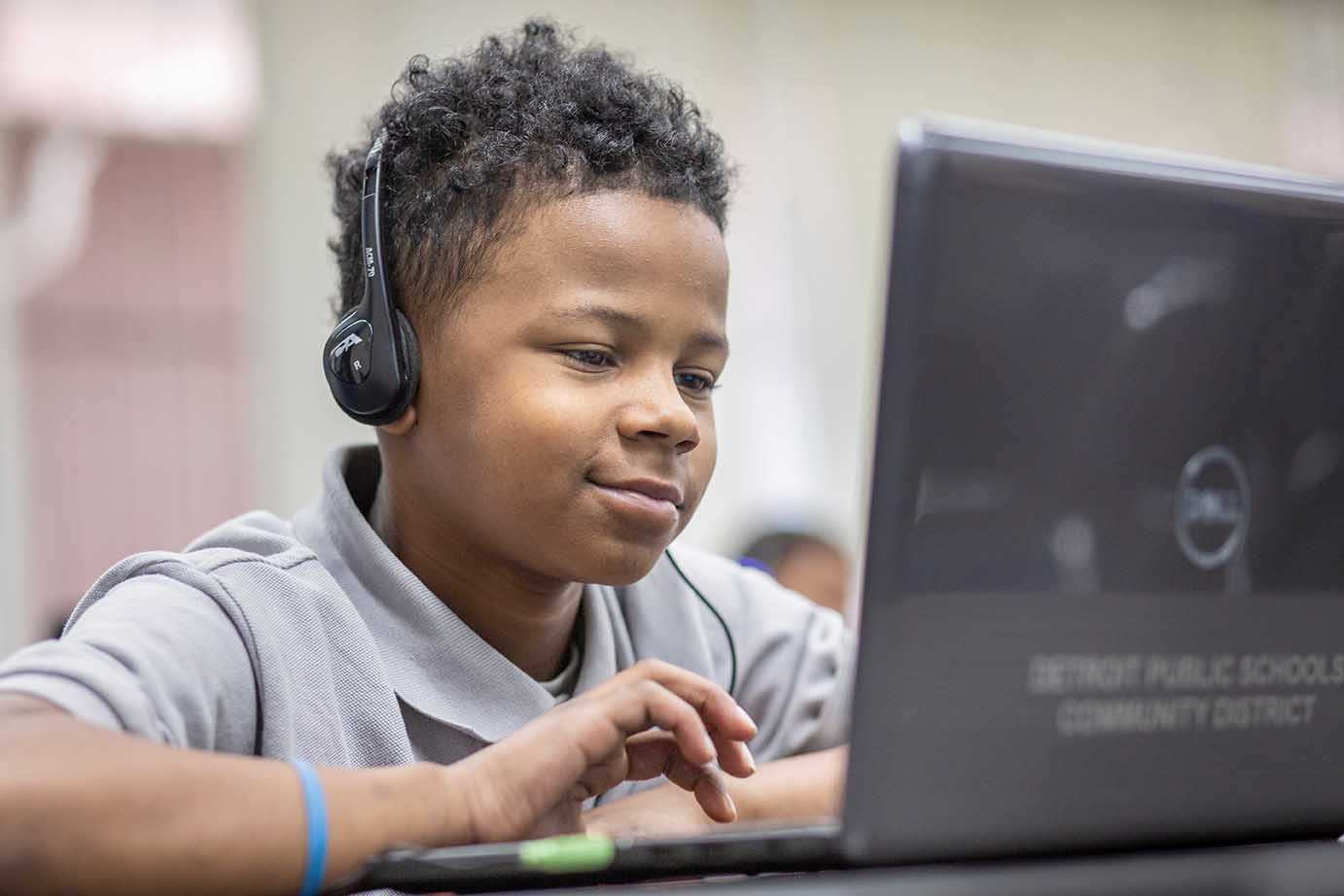  Young boy working on a laptop with headphones.